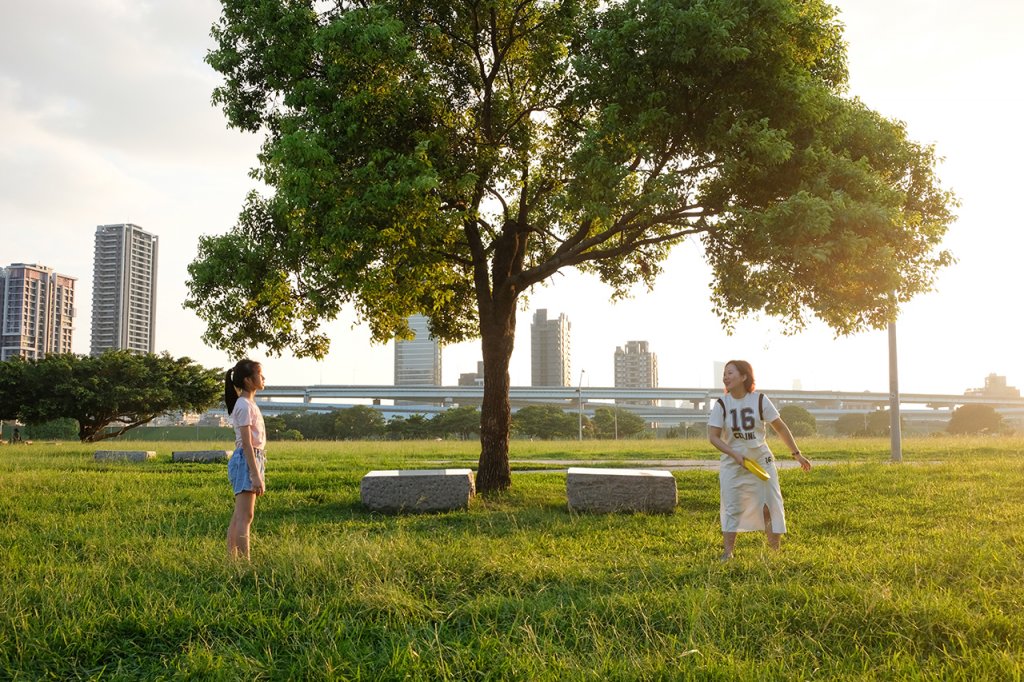 楊亞嬌與女兒在草地上玩著飛盤，盡情享受親子時光。