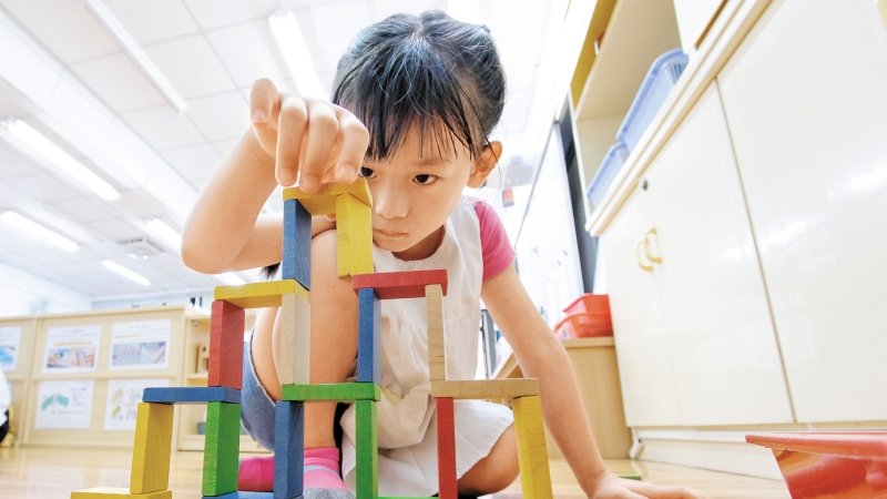 ▲幼兒園的STEAM課程：女孩專注搭建ㄇ字大樓骨牌，正挑戰超越11層樓。楊煥世攝